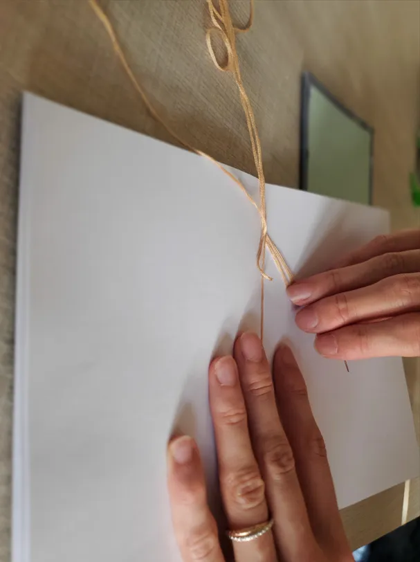 Juliette Alcaraz en train de relier les pages d'un carnet, 2025